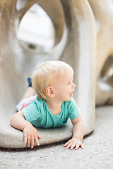 Image showing Child playing on outdoor playground. Toddler plays on school or kindergarten yard. Active kid on stone sculpured slide. Healthy summer activity for children. Little boy climbing outdoors.