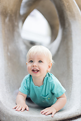 Image showing Child playing on outdoor playground. Toddler plays on school or kindergarten yard. Active kid on stone sculpured slide. Healthy summer activity for children. Little boy climbing outdoors.