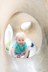 Image showing Child playing on outdoor playground. Toddler plays on school or kindergarten yard. Active kid on stone sculpured slide. Healthy summer activity for children. Little boy climbing outdoors.