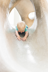 Image showing Child playing on outdoor playground. Toddler plays on school or kindergarten yard. Active kid on stone sculpured slide. Healthy summer activity for children. Little boy climbing outdoors.