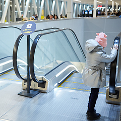 Image showing Back view of child going on escalator background. Shopping mall, airport travel, love care, protection concept