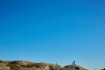 Image showing Silhouette of young active man with bicycle standing and looking forward at mountains panoramic background