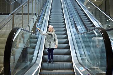 Image showing From below shot of girl standing on moving stairs in terminal.