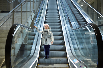 Image showing From below shot of girl standing on moving stairs in terminal.