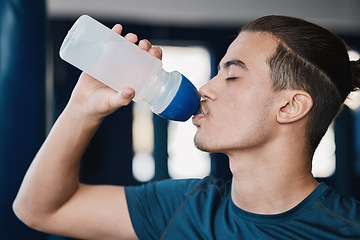 Image showing Thirsty, fitness and a man drinking water after exercise at the gym for wellness and health. Hydration, young and a male athlete with a bottle for liquid after cardio, workout or training on a break