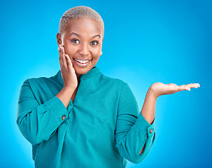 Image showing Portrait, smile and black woman showing, presentation and promotion against a blue studio background. Face, female person or model with discount deal, option and choice with decisions and advertising