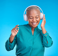 Image showing African woman, headphones and studio for listening, music and smile with dancing by blue background. Young gen z student, sound tech and happy for audio streaming, online radio and excited with dance