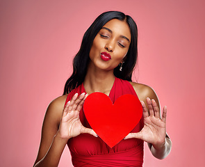 Image showing Kiss, heart and valentines day with a woman on a pink background in studio for love or romance. Red lips, emoji and social media with a happy young female holding a shape or symbol of affection
