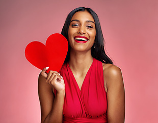 Image showing Portrait, heart and social media with a woman on a pink background in studio for love or romance. Smile, emoji and valentines day with a happy young female holding a shape or symbol of affection