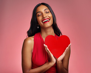 Image showing Smile, heart and valentines day with a woman on a pink background in studio for love or romance. Eyes closed, emoji and social media with a happy young female holding a shape or symbol of affection