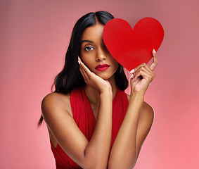 Image showing Woman, paper heart and face in studio portrait for makeup, beauty or romantic sign by red background. Girl, fashion model and cardboard emoji with love for cosmetic, valentines day date and aesthetic