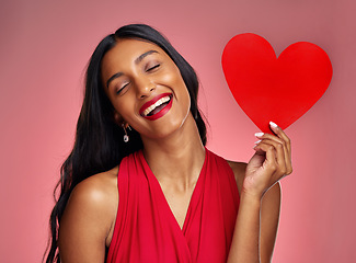 Image showing Funny, heart and valentines day with a woman on a pink background in studio for love or romance. Smile, emoji and social media with a young female comic holding a shape or symbol of affection