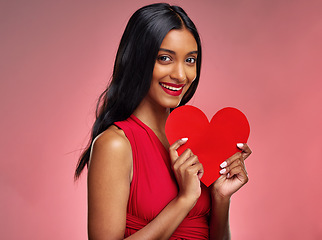 Image showing Portrait, heart and valentines day with a woman on a pink background in studio for love or romance. Smile, emoji and social media with a happy young female holding a shape or symbol of affection