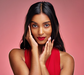 Image showing Woman, red lipstick and beauty, hands touching face with makeup and cosmetics glow on pink background. Cosmetology, Indian female model in portrait and shine with wellness and skincare in studio