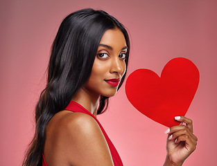 Image showing Portrait, heart and love with a woman on a pink background in studio for romance on valentines day. Face, emoji and social media with a confident young female holding a shape or symbol of affection