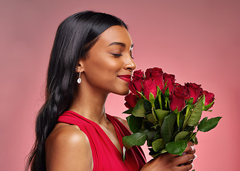 Image showing Face, beauty and a woman smelling a roses on a studio background for valentines day. Makeup, model and happy young Indian girl profile with a flower bouquet for romance or love on pink backdrop