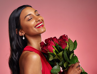 Image showing Face, beauty and smile of a woman with a roses on a studio background for valentines day. Makeup, model and happy young Indian girl with a flower bouquet for romance or love on a pink backdrop