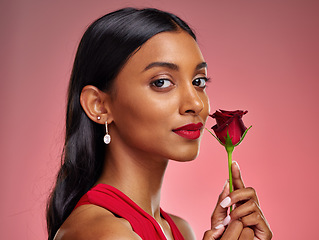 Image showing Beautiful, portrait and an Indian woman with a rose on a studio background for valentines day. Serious, model and face of a young girl with a flower for romance or love isolated on a backdrop