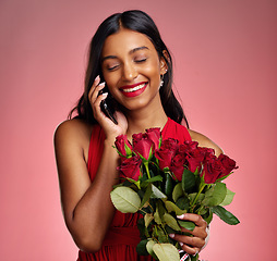 Image showing Phone call, talking and a happy woman with flowers on a studio background for valentines day. Laugh, model and face of a young Indian girl with a rose bouquet and smartphone for romance or love