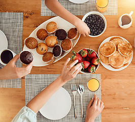 Image showing Breakfast, food and hungry people in dining room, eating healthy and above table setting or home in the morning. Fruit, pancakes and hands on strawberry or muffin plate for nutrition or diet