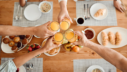 Image showing Lunch, hands and people toast with orange juice, beverage or glass drinks at lunch, brunch or food meal. Fruit liquid, top view group and home family solidarity, celebrate and cheers at social event