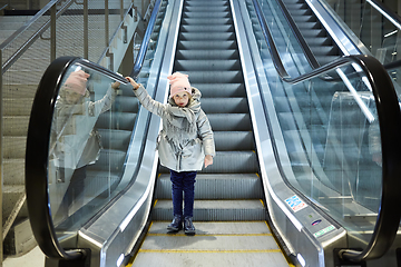 Image showing From below shot of girl standing on moving stairs in terminal.