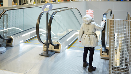 Image showing Back view of child going on escalator background. Shopping mall, airport travel, love care, protection concept