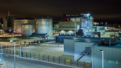 Image showing Modern grain terminal at night. Metal tanks of elevator. Grain-drying complex construction. Commercial grain or seed silos at seaport. Steel storage for agricultural harvest