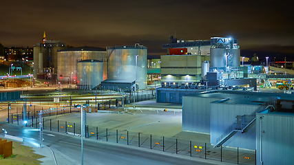 Image showing Modern grain terminal at night. Metal tanks of elevator. Grain-drying complex construction. Commercial grain or seed silos at seaport. Steel storage for agricultural harvest