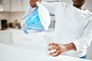 Image showing Person, jug and glass of filter water in kitchen for fresh drink, liquid and hydration. Closeup, thirsty woman or pouring pure aqua beverage in container for nutrition, drinking or filtration at home