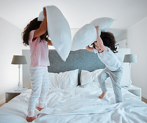 Image showing Happy siblings, pillow fight and playing on bed in morning together for fun bonding at home. Little girls, children or kids enjoying playful game, entertainment or fighting with pillows in bedroom