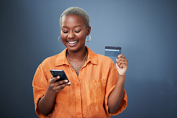 Image showing Smile, phone and credit card with a black woman online shopping in studio on a gray background. Mobile, ecommerce and finance payment with a happy young female shopper searching for a deal or sale