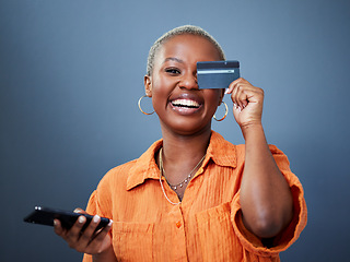 Image showing Portrait, phone and credit card with a black woman online shopping in studio on a gray background. Mobile, ecommerce and funny humor with a young female shopper looking excited for a deal or sale