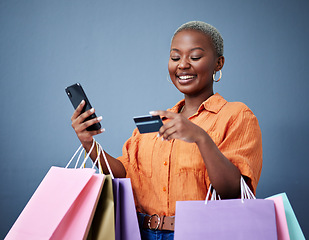 Image showing Bags, retail and black woman with a credit card, smartphone or ecommerce on a grey studio background. Female person, shopper or model with cellphone, boutique items or purchase with shopping or smile