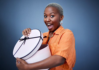 Image showing African woman, open present or box in studio portrait with excited smile, surprise and blue background. Girl, happy and wow with package, gift and fashion for celebration, winner and birthday party