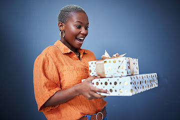 Image showing Black woman, gift package and surprise in studio with excited smile, giveaway and blue background. African girl, happy and wow with box, present and fashion for celebration, winner and birthday party