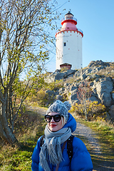 Image showing Beautiful woman posing near lighthouse. Travel the world concept