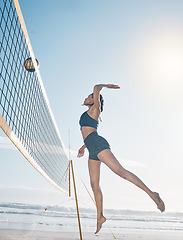 Image showing Woman, jump and volleyball player on beach by net in serious sports match, game or competition. Fit, active and sporty female person jumping or reaching for ball in volley or spike by the ocean coast