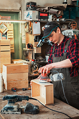 Image showing Worker grinds the wood box