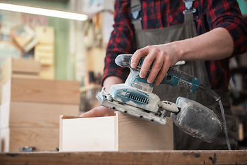 Image showing Worker grinds the wood box