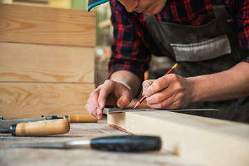 Image showing The worker makes measurements of a wooden board