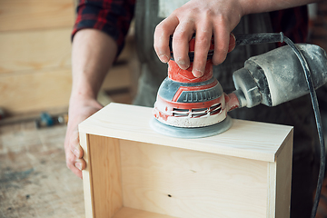 Image showing Worker grinds the wood box