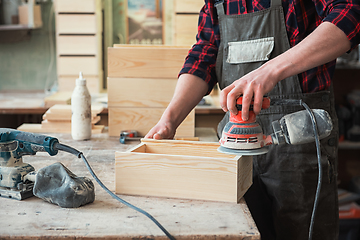 Image showing Worker grinds the wood box