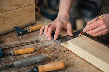 Image showing The worker makes measurements of a wooden board