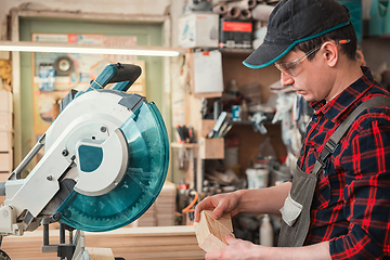 Image showing Construction worker cutting wooden board