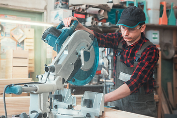 Image showing Construction worker cutting wooden board