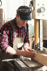 Image showing Construction worker cutting wooden board