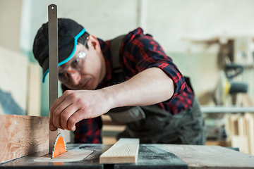 Image showing The worker makes measurements of a wooden board