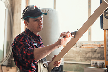 Image showing The worker makes measurements of a wooden board