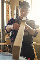 Image showing The worker makes measurements of a wooden board